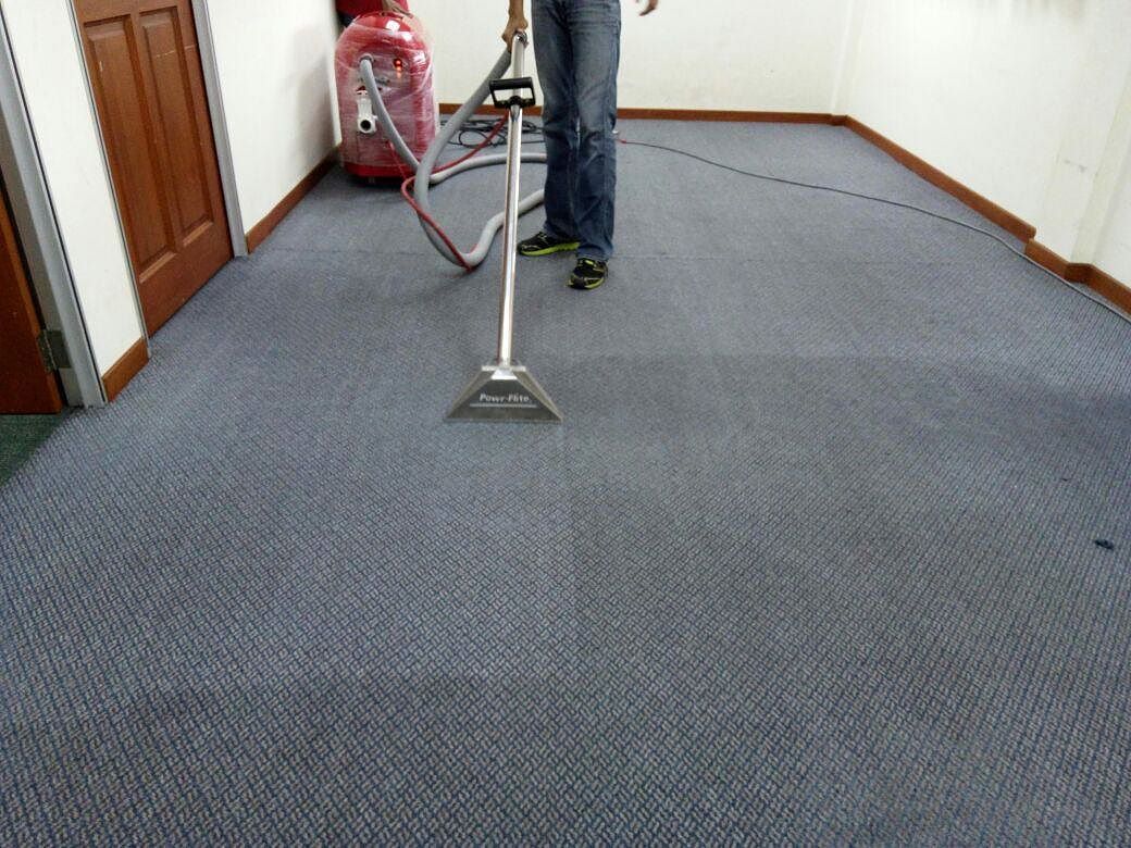 Technician using an injection-extraction wand on commercial carpet
